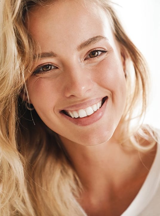 Nahaufnahme des Gesichts einer lachenden blonden Frau.